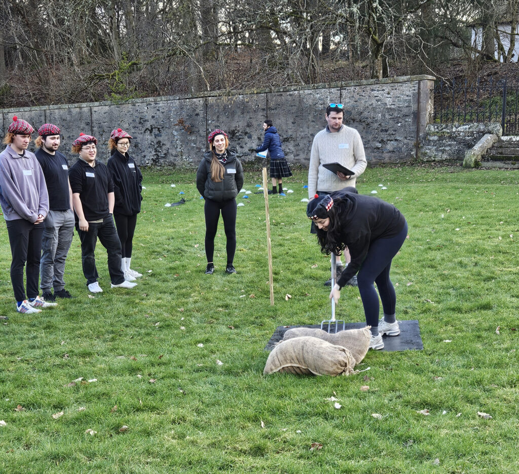 Student bending down to pitch a hay bag during the Highland Games