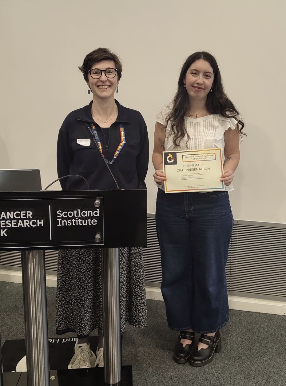 Kay holding her prize certofocate with the person who presnted her with teh certificate